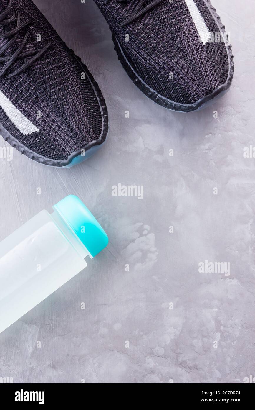 Concept fitness avec baskets et bouteille d'eau. Équipement sportif sur fond gris. Concept de mode de vie sain. Copier l'espace. Vue de dessus Banque D'Images