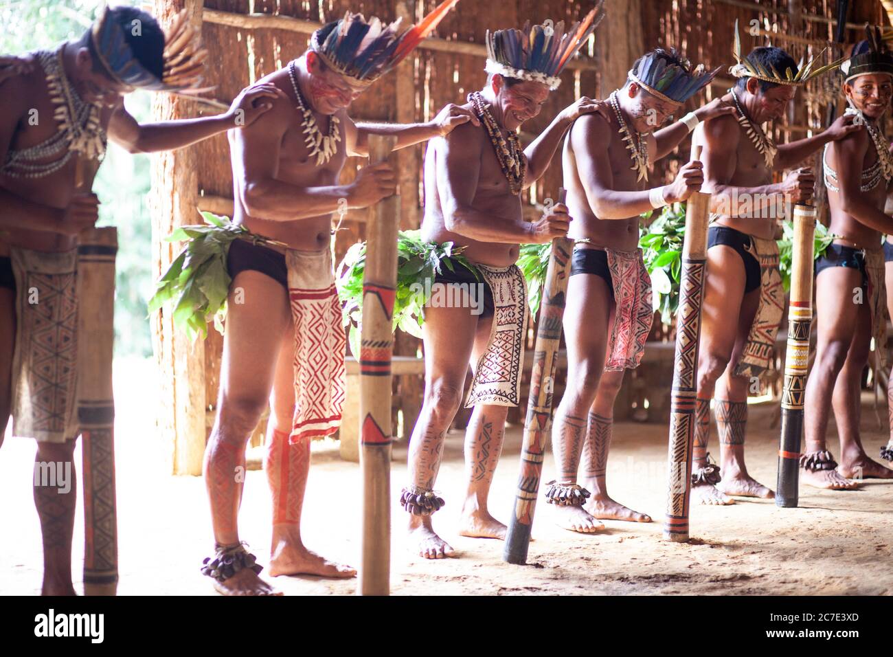 Les hommes indigènes amazoniens exécutent une cérémonie tribale traditionnelle avec des bâtons de cérémonie, portant des coiffes à plumes et de la peinture corporelle, célébrant leur cérémonie Banque D'Images
