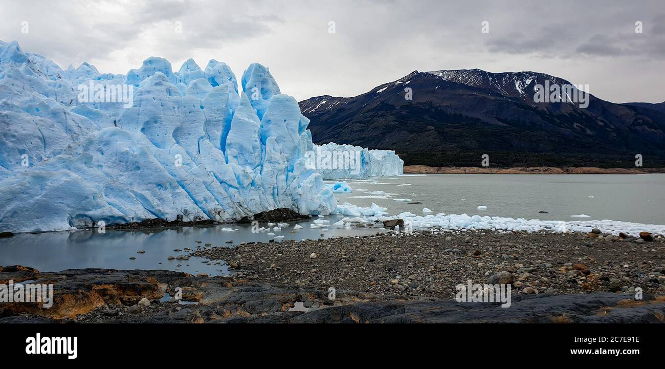 Glacier Perito Moreno avec de mini icebergs dans l'eau autour de lui et des montagnes en arrière-plan Banque D'Images