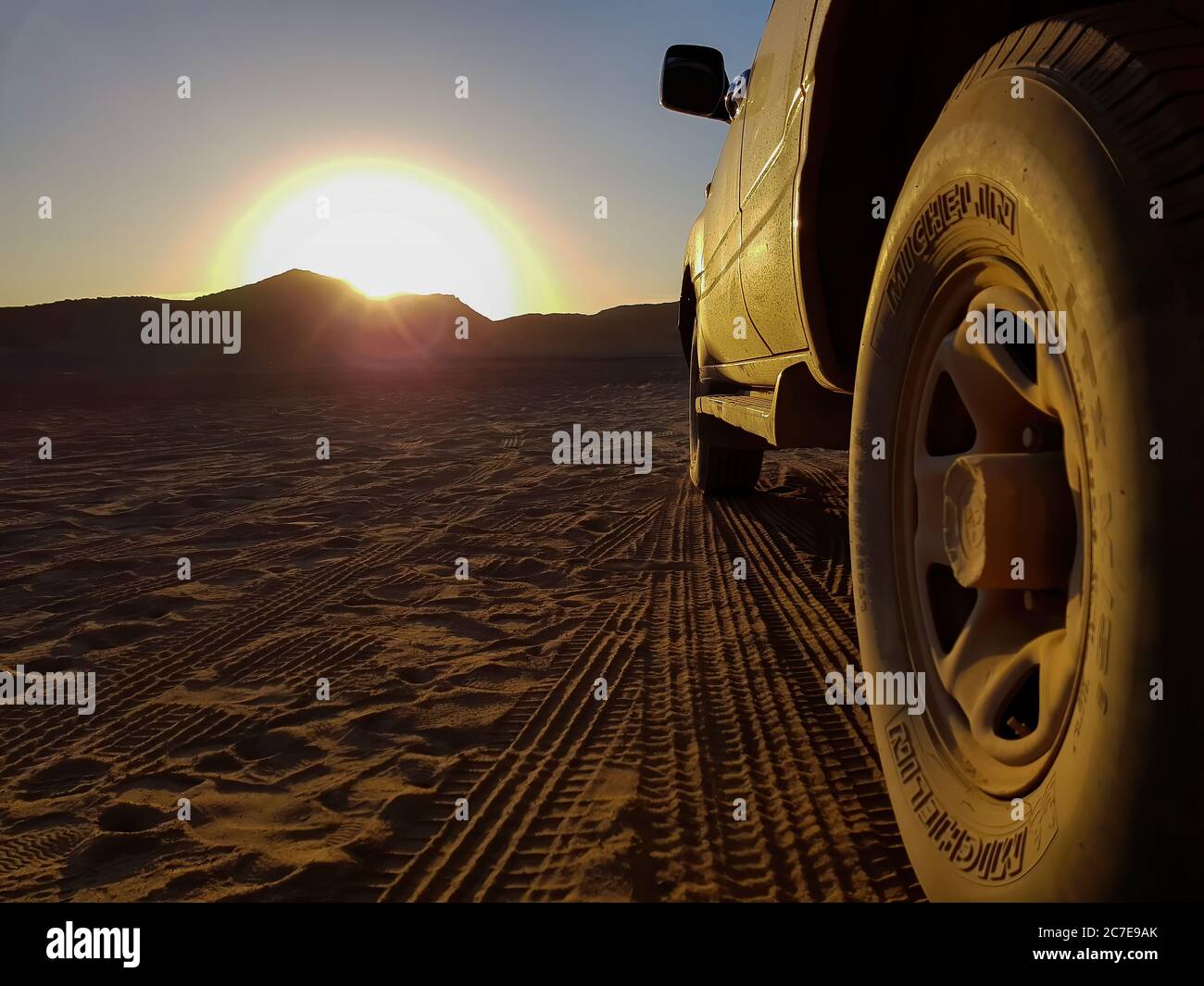 Gros plan sur les roues d'un camion 4x4 dans un désert au coucher du soleil Banque D'Images