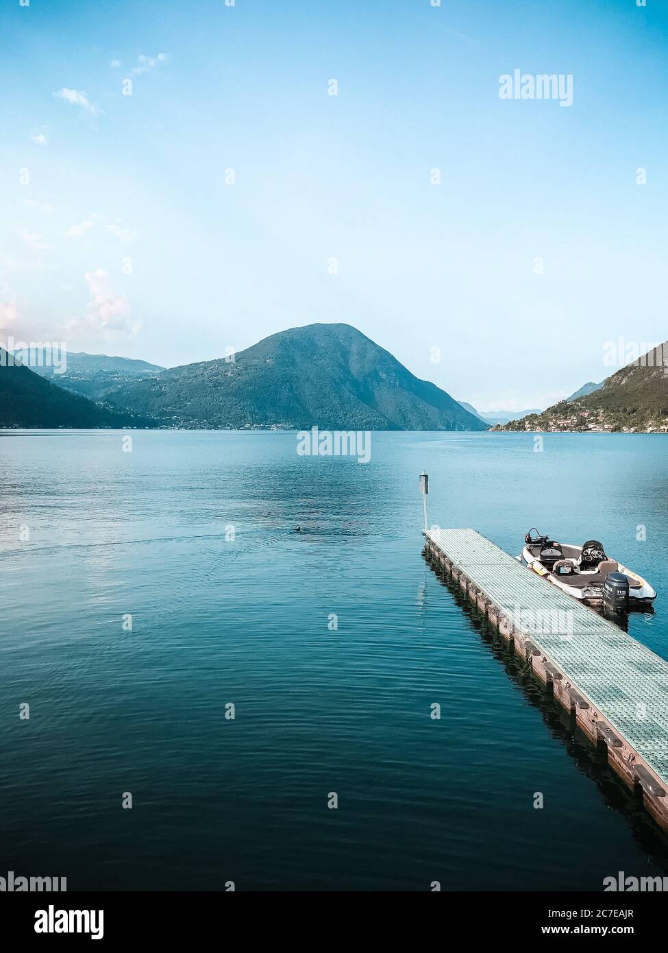 Plan vertical d'un bateau près d'un quai en bois la mer avec de belles montagnes vertes Banque D'Images