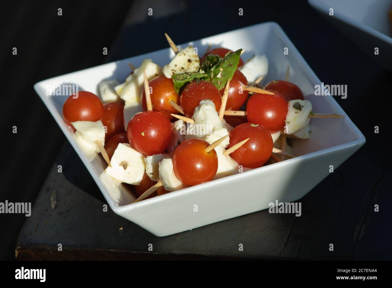 Bol d'en-cas de mozzarella et tomates cerises assaisonnées de basilic frais et d'huile d'olive Banque D'Images