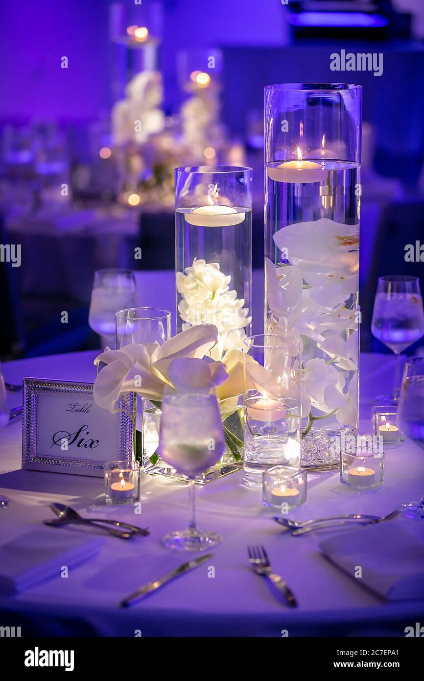 Tables de cérémonie de mariage à l'ambiance bleue avec un récipient en verre éclairé et des bougies flottantes Banque D'Images