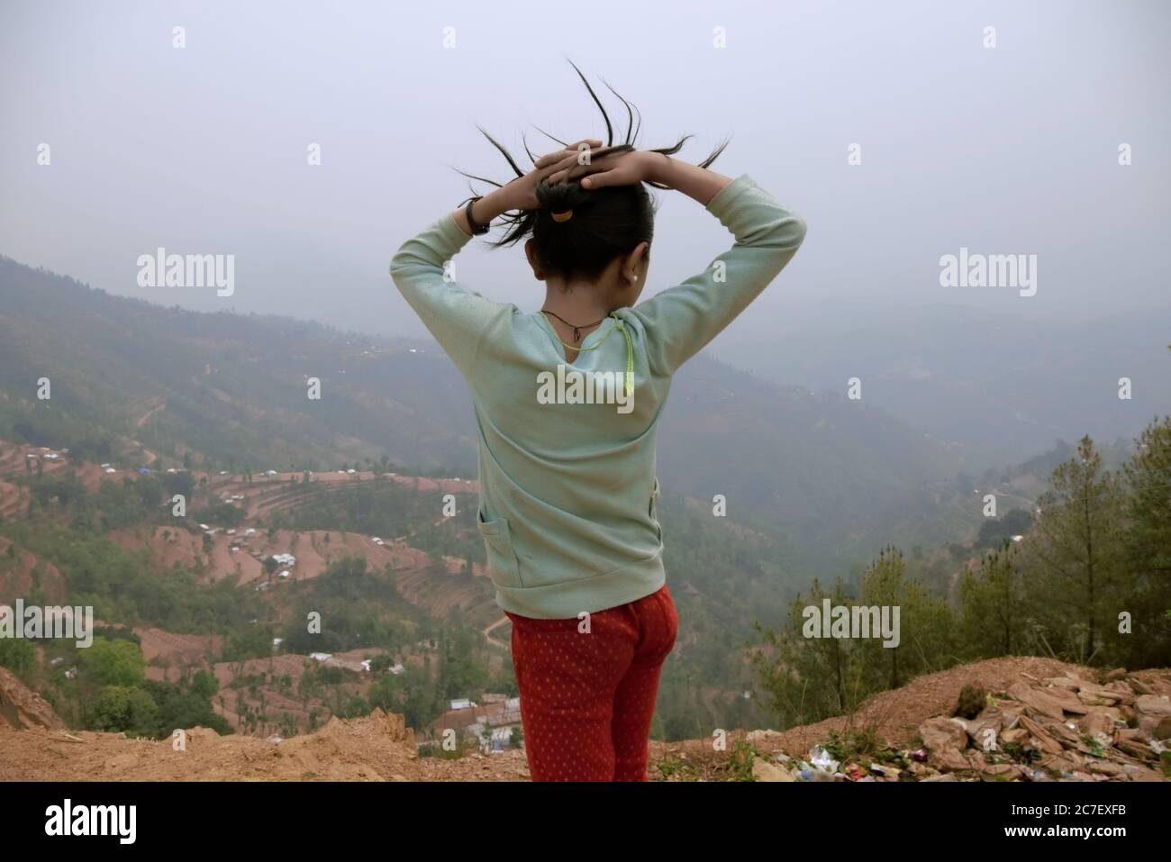 Portrait arrière d'un enfant qui surplombe une vallée fortement touchée par les tremblements de terre et les glissements de terrain de 2015 dans le village de Chandani Mandan, Kavrepalanchok, au Népal. Banque D'Images