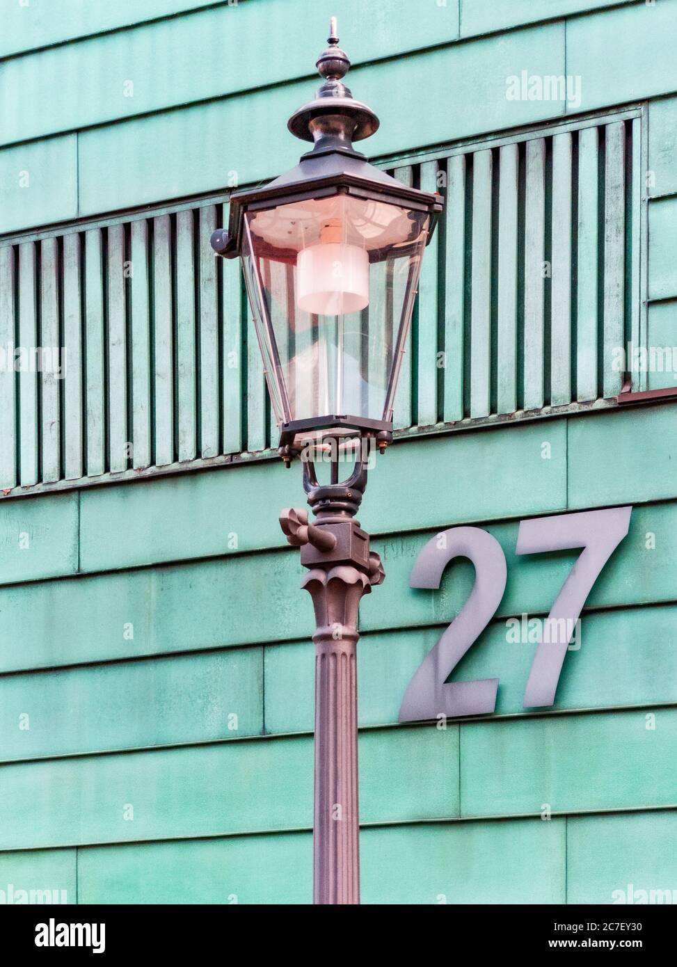 Photo verticale d'une lumière de rue devant un bâtiment vert avec le numéro 27 Banque D'Images