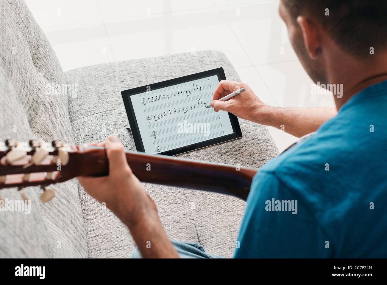 Homme composant de la musique de guitare acoustique sur tablette numérique Banque D'Images