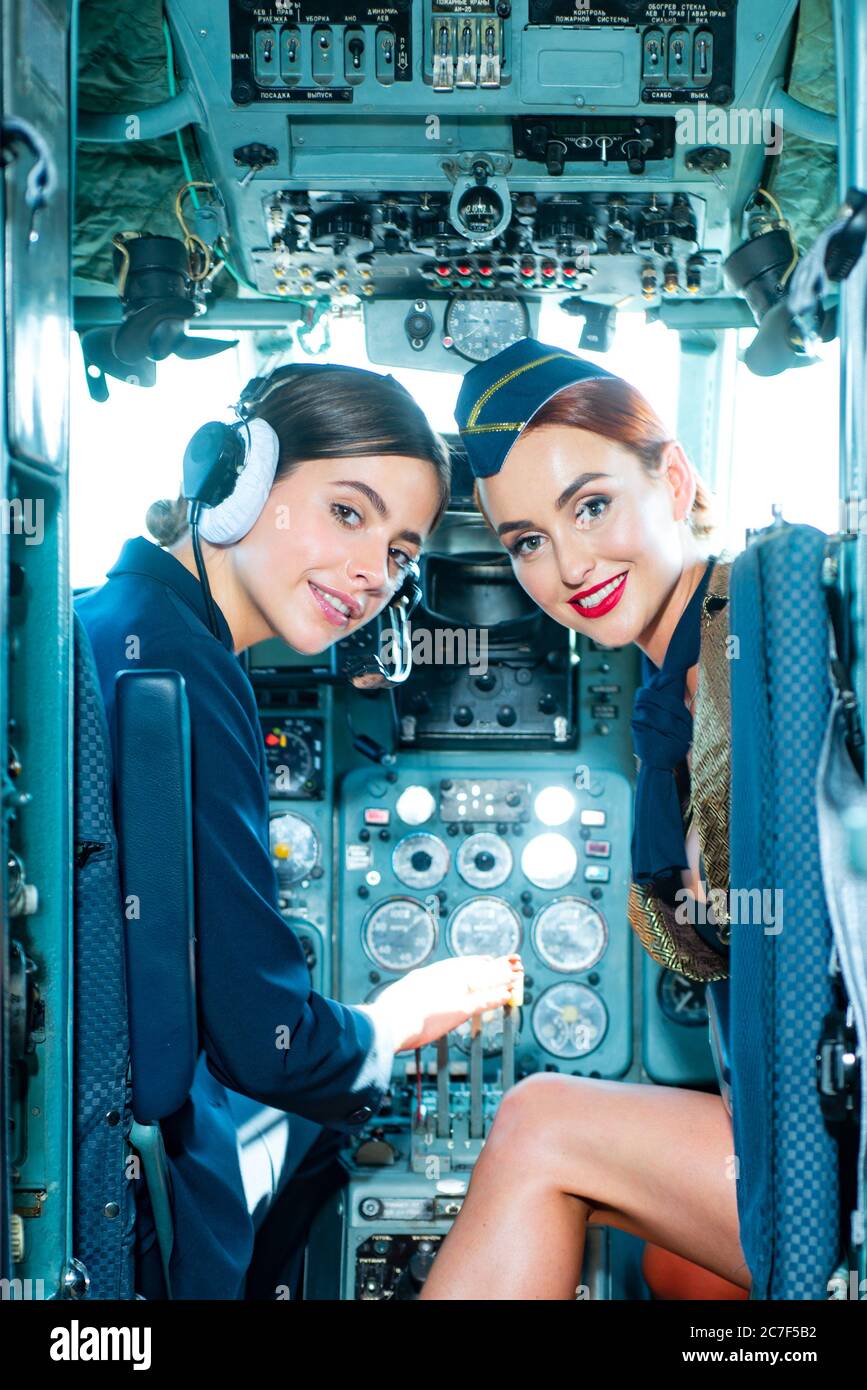 Deux belles femmes pilote portant un uniforme. Regarder la caméra à travers le cockpit. Pilotes dans le cockpit. Filles regardant l'appareil photo. Heureux et réussi Banque D'Images