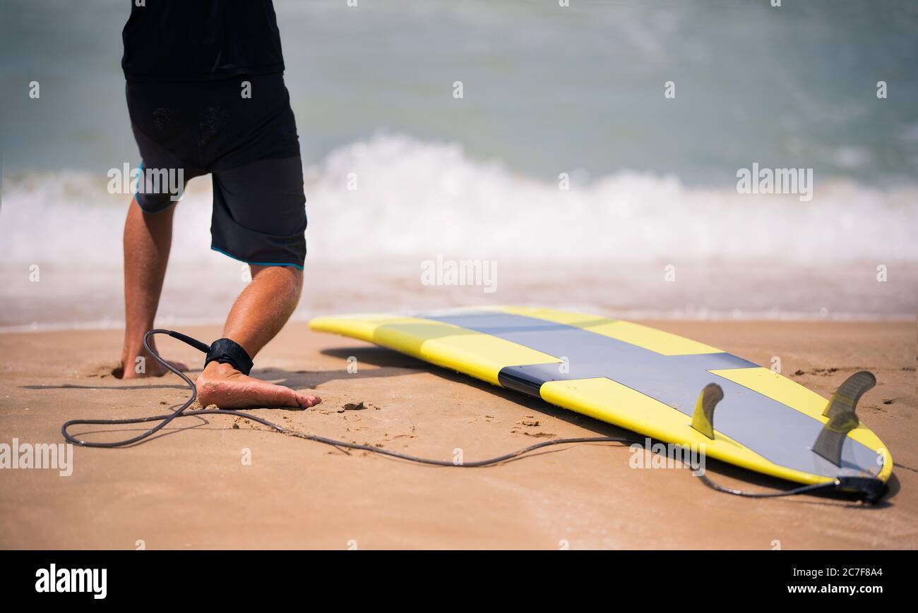 Un instructeur de surf montre sur la plage ensoleillée comment se tenir sur la planche de surf. Cours de surf Banque D'Images