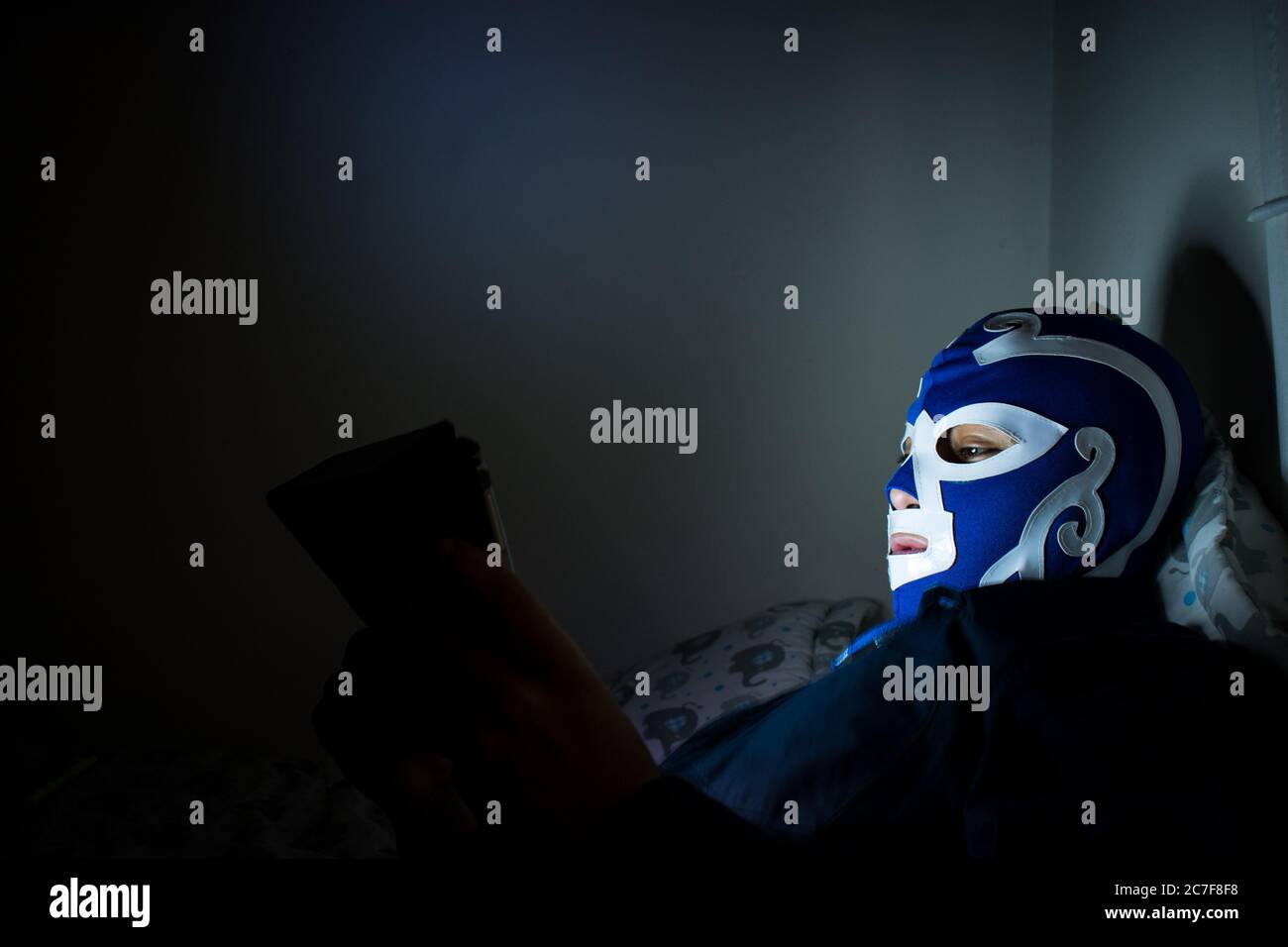 Homme portant un masque de lutte bleu dans sa chambre travaillant avec l'ordinateur portable Banque D'Images