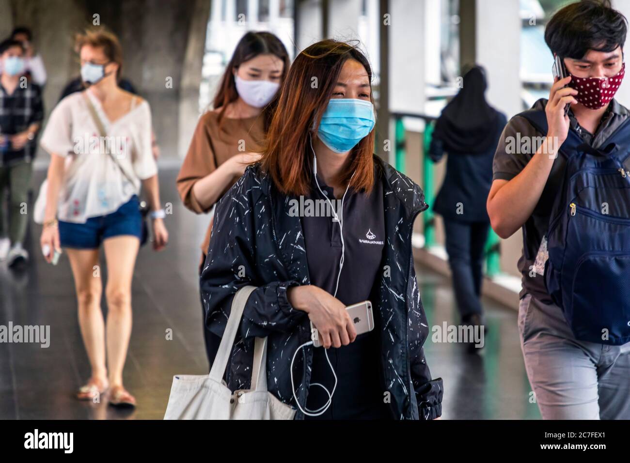 Piétons portant un masque facial avec un téléphone mobile pendant la pandémie Covid 19, Bangkok, Thaïlande Banque D'Images