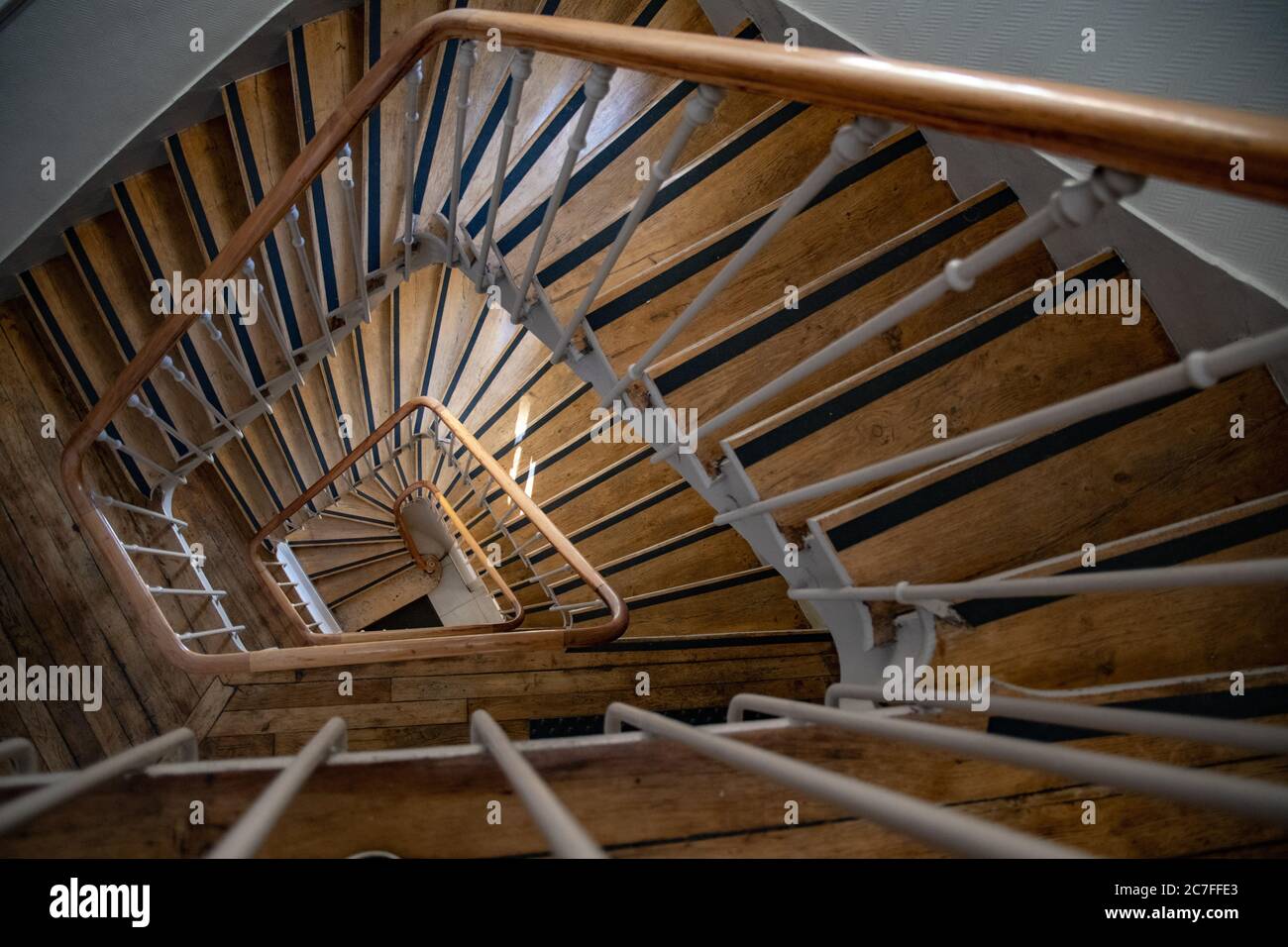 Vue de dessus sur les escaliers en spirale d'époque du bâtiment ancien. Détails architecturaux de style français de l'escalier avec marches en bois et rambardes en métal ornées Banque D'Images