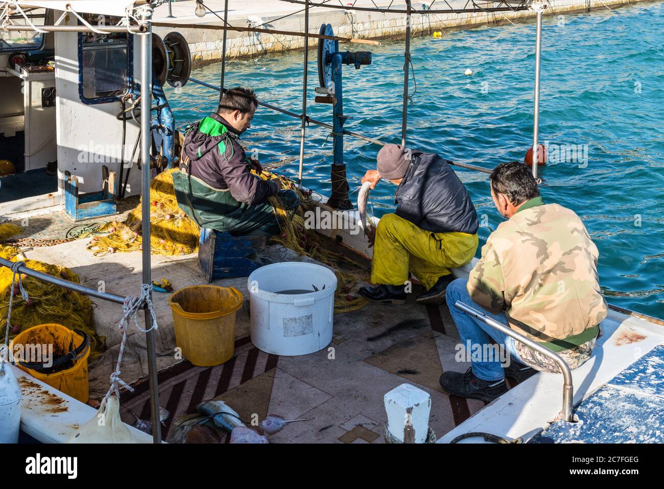 Katakolo, Grèce - 11 novembre 2019 : pêcheurs grecs partageant les prises après avoir pêché dans son bateau. La pêche dans les bateaux traditionnels en bois reste un impo Banque D'Images