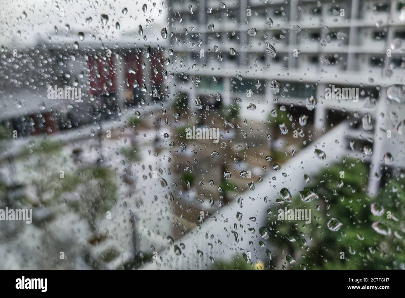 parking de condominium moderne urbain pendant un orage. pluie en ville. goutte d'eau prise sur la façade de fenêtre en verre. Banque D'Images