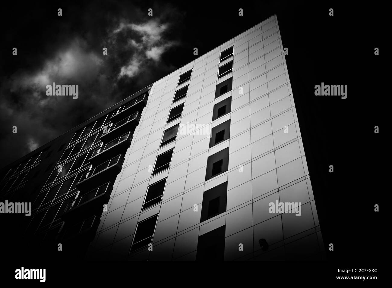 Vue en niveaux de gris d'un immeuble d'appartements sous le nuages de tempête Banque D'Images