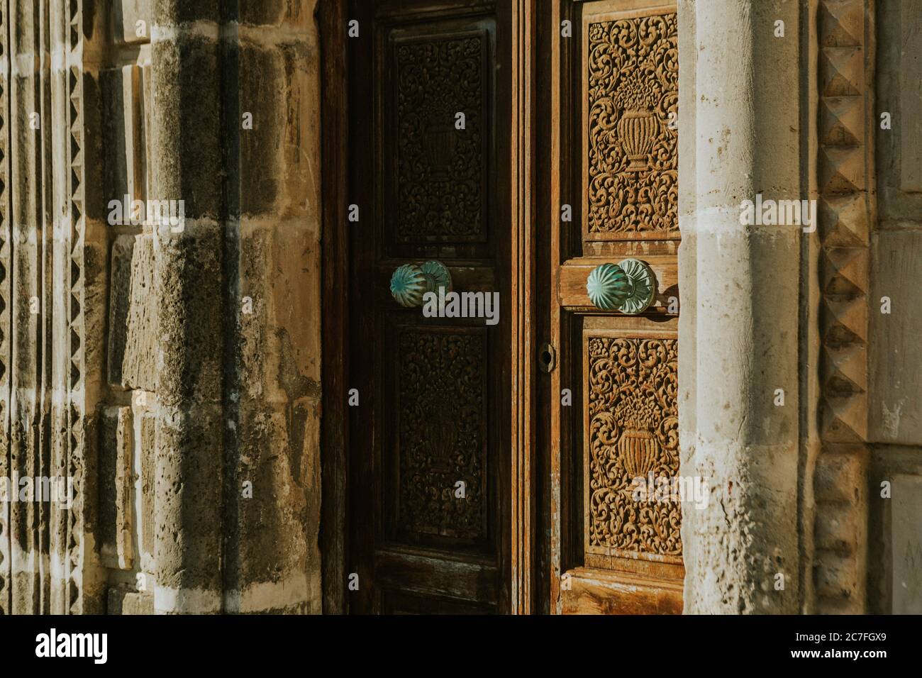 Détail de vieilles portes ornementales en bois sculpté fermées de l'église avec poignée ronde en cuivre recouverte de verdigris sur lumière du soleil Banque D'Images