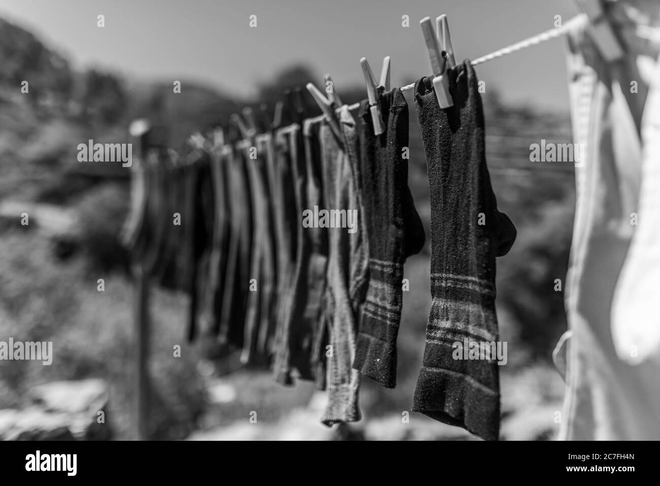 Niveaux de gris des chaussettes lavées sur une ligne dans un champ entouré de collines sous le soleil Banque D'Images