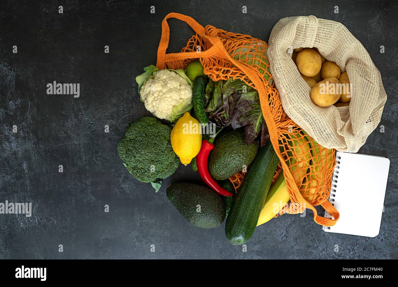 Un concept de vie sans plastique. Fruits et légumes dans un sac à ficelle avec un carnet vide pour une liste de produits. Banque D'Images