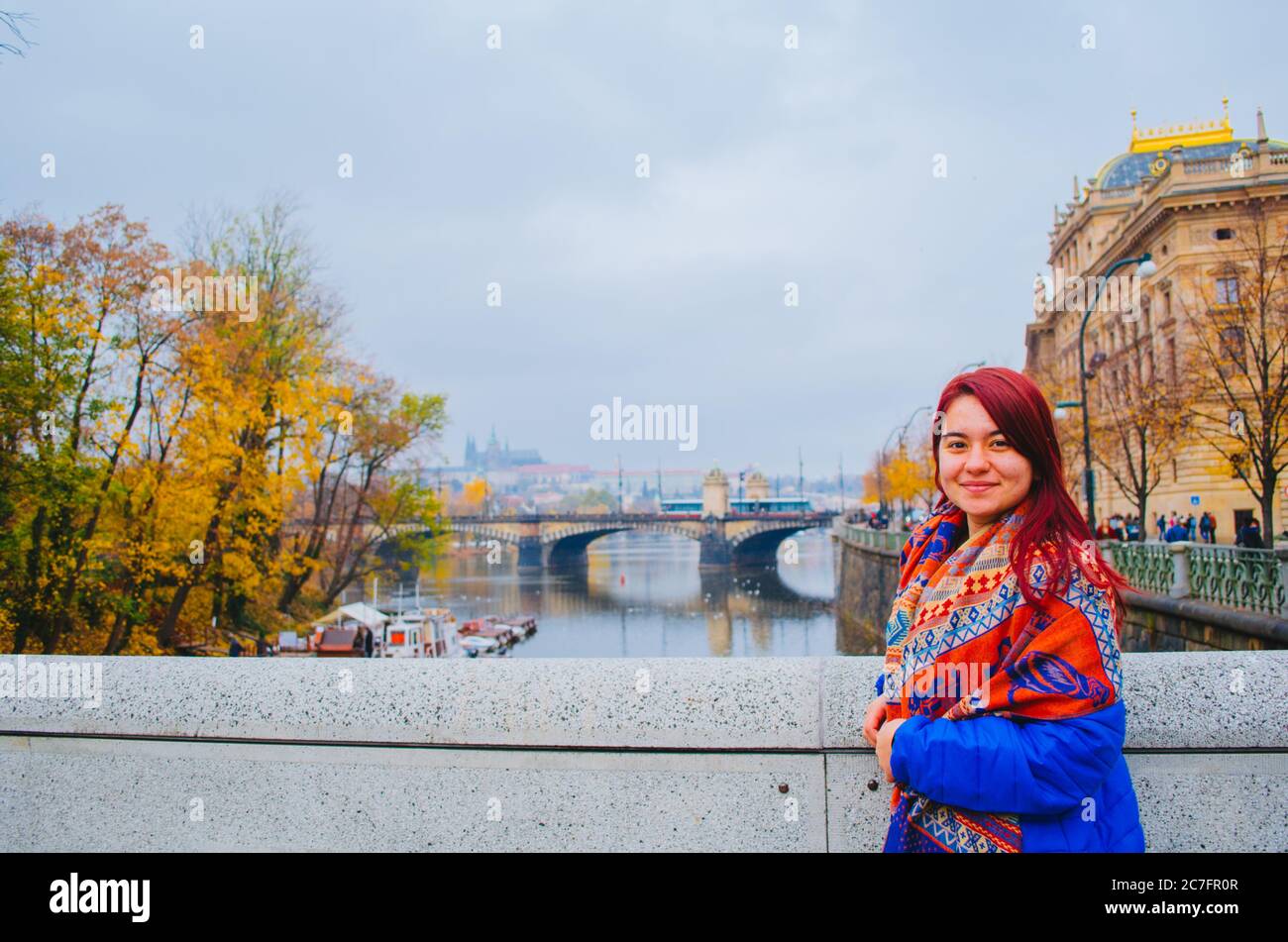 Une brésilienne à tête rouge dans ses 20 ans devant un pont à Prague, en Tchéquie et souriant à la caméra. Banque D'Images