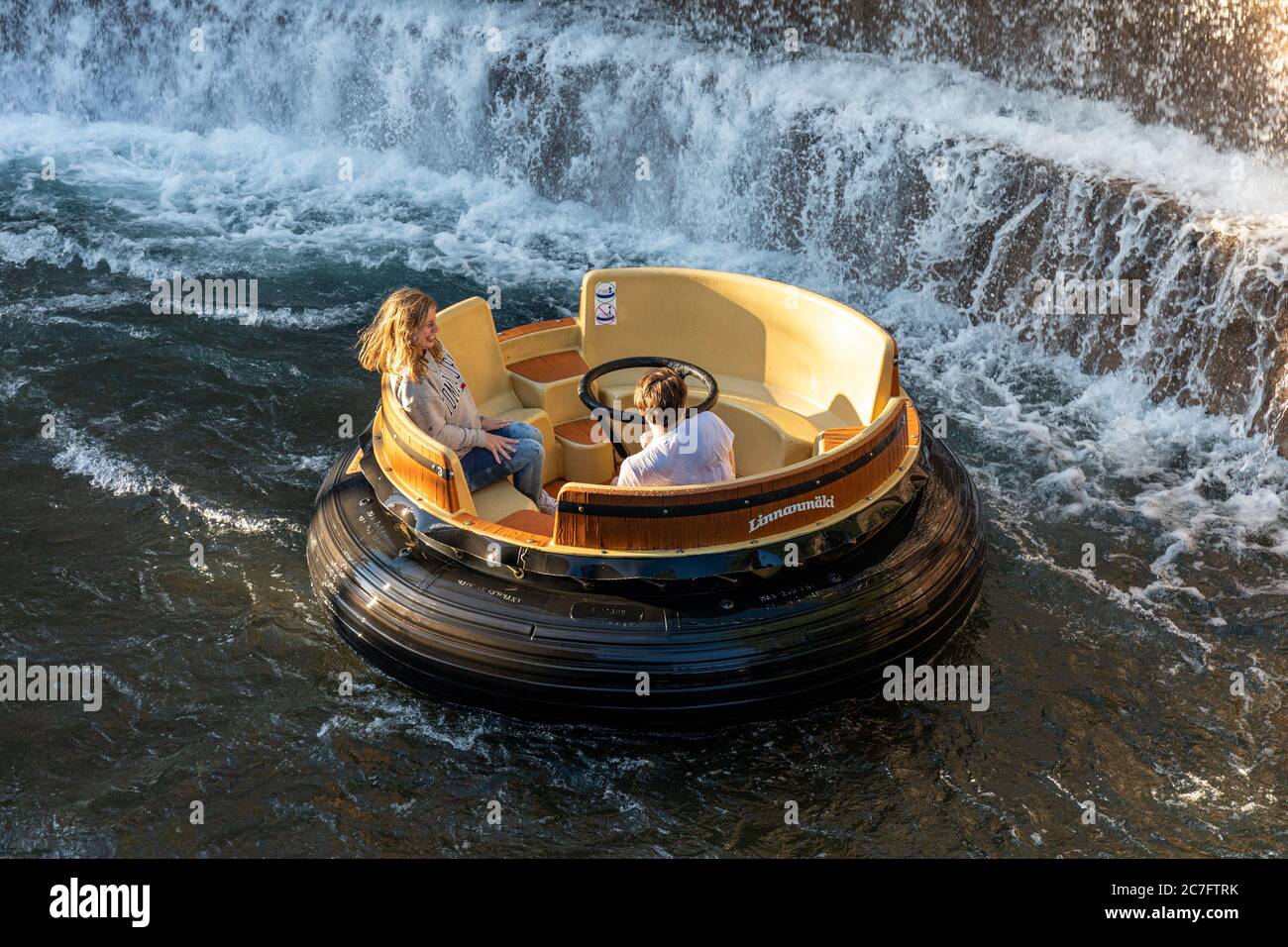 Couple essayant d'éviter de s'mouiller sur un radeau circulaire de rapides de la rivière Hurjakuru dans le parc d'attractions Linnanmäki à Helsinki, Finlande Banque D'Images