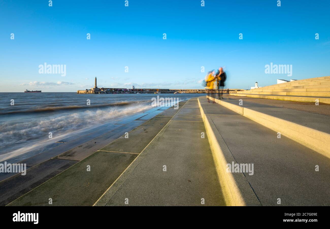 Un couple marchant sur le front de mer de Margate en face de l'arbras du port avec le Turner Contemporary et la maison de droit en arrière-plan. Banque D'Images