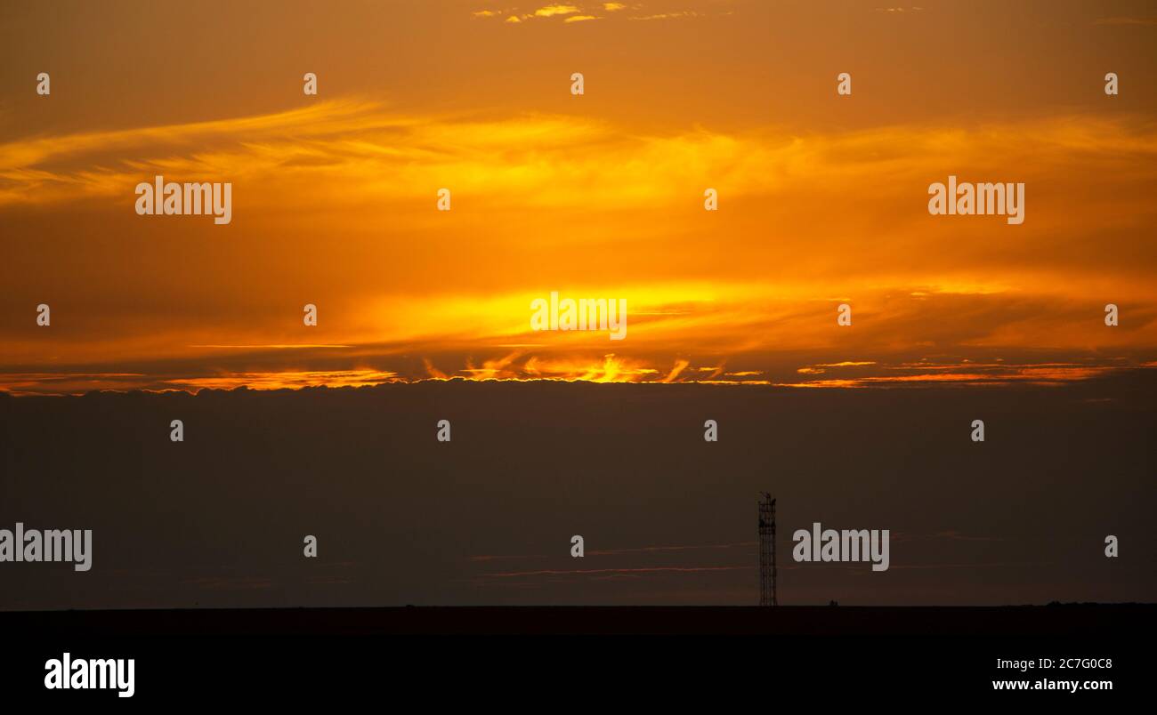 Langues de flamme de derrière les nuages au coucher du soleil, magnifique coucher de soleil rouge derrière les nuages. Banque D'Images