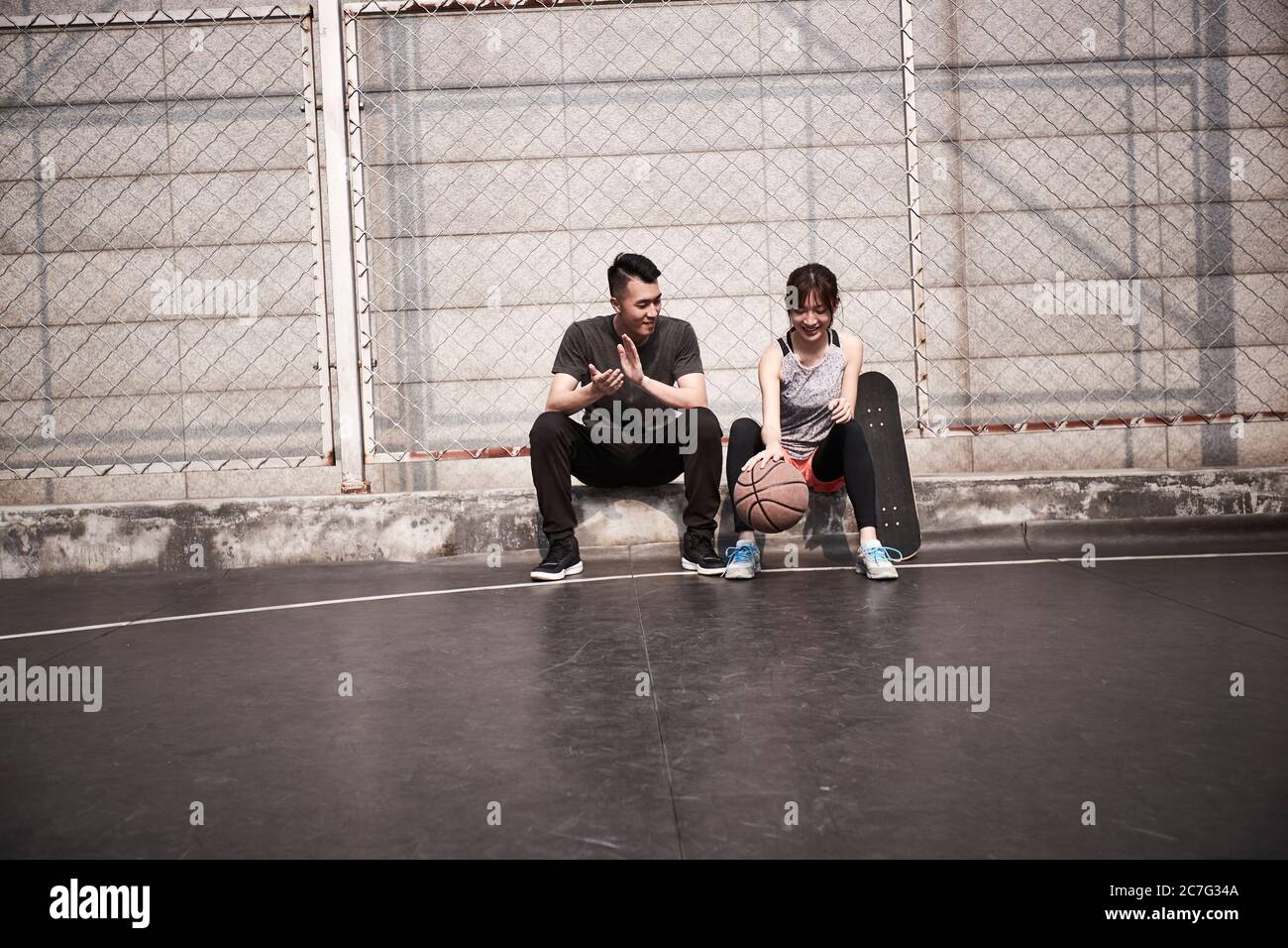 jeune homme et femme asiatique adulte se reposant et jouant avec le basket-ball sur le terrain Banque D'Images
