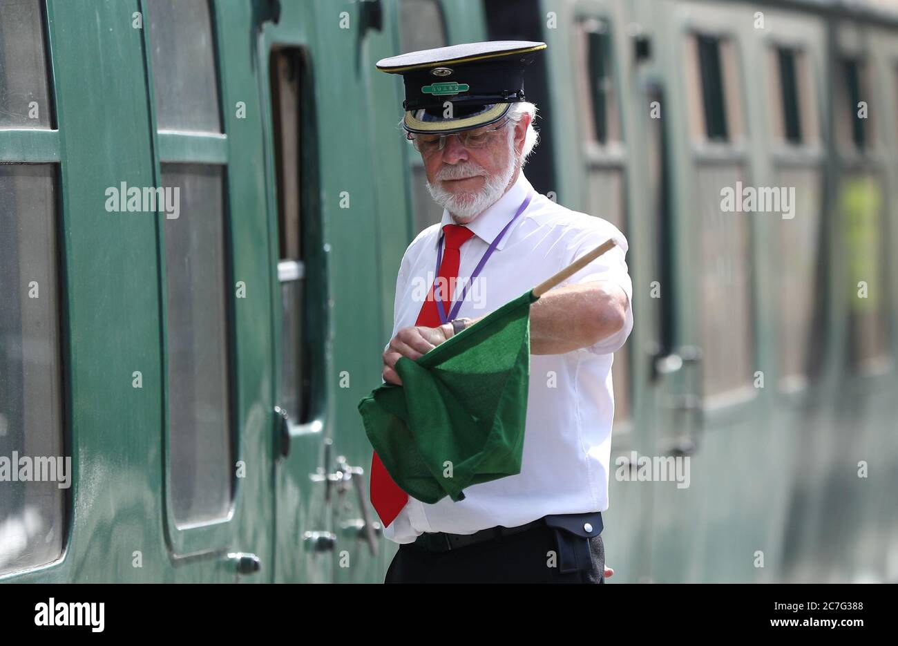 Le garde Ian Coane vérifie sa montre sur la plate-forme de la gare de Swanage, alors que les dernières préparations sont faites au chemin de fer de Swanage avant la course des trains à vapeur pour la première fois depuis le verrouillage du coronavirus en mars. Le chemin de fer patrimonial de l'île de Purbeck, Dorset, utilisera de nouveau samedi des moteurs à vapeur avec un service sans escale entre les gares de Swanage et Norden avec une distanciation sociale en place aux gares et sur les trains et le port de revêtements de visage. Banque D'Images