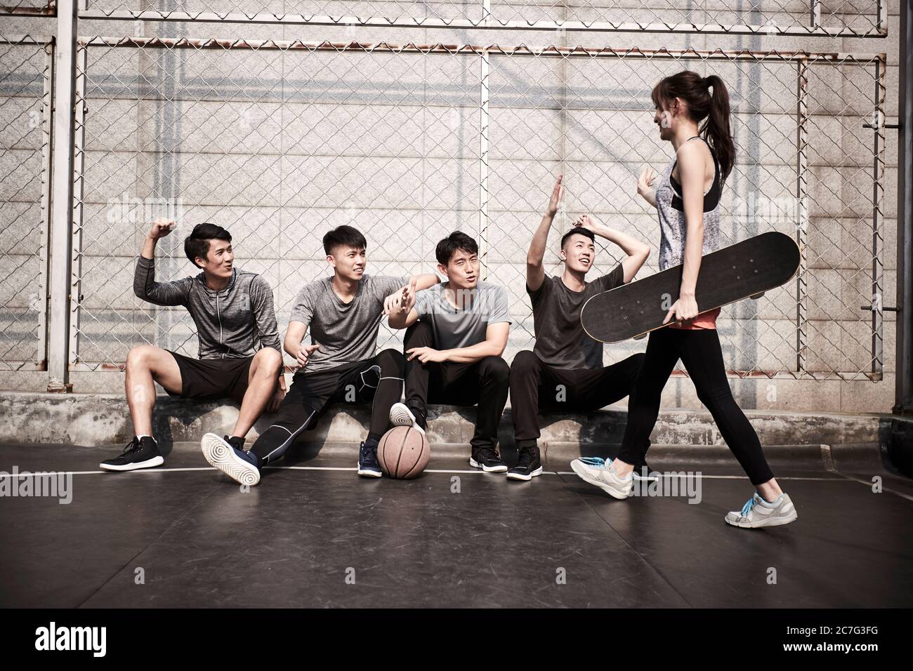 jeune femme adulte asiatique skateboarder donnant un groupe de jeunes hommes hi-cinq Banque D'Images