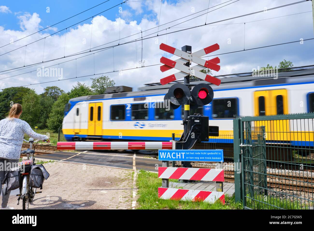 Passage de chemin de fer avec barrières et feux rouges clignotants et train à grande vitesse peu tranchant. Texte hollandais, attendre jusqu'à ce que la lumière rouge soit disparu, possibilité d'autre train Banque D'Images