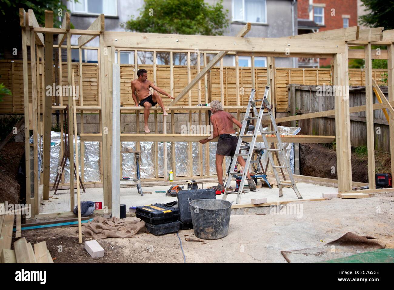 Deux constructeurs construisant le cadre en bois pour un studio de jardin Banque D'Images