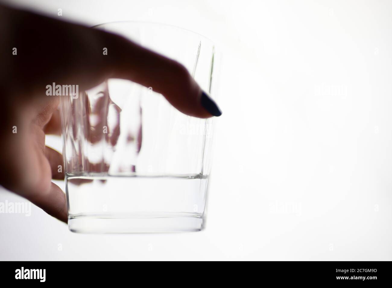 Un verre d'eau dans une main femelle sur un fond blanc isolé. Banque D'Images