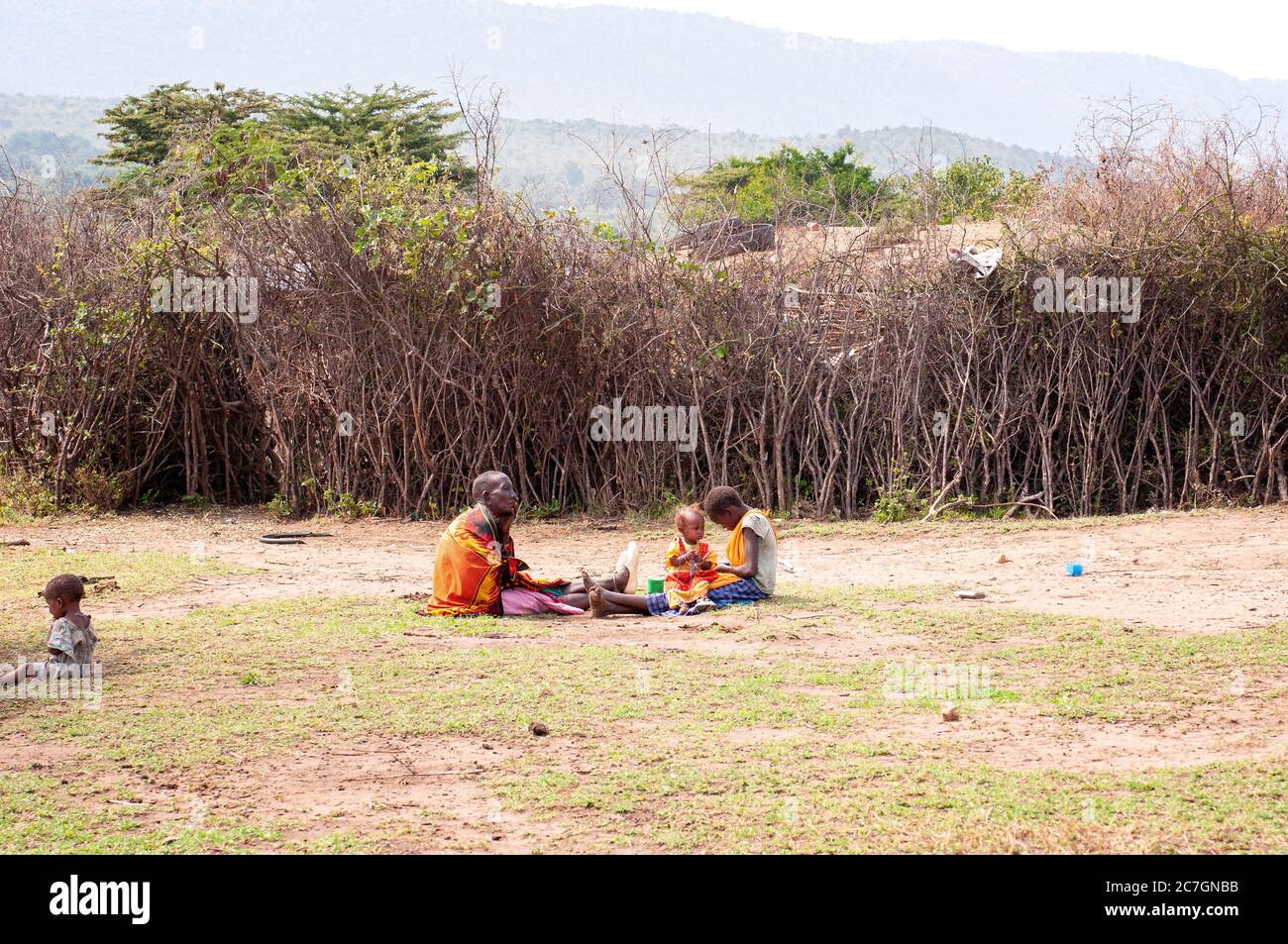 La famille Maasai portant une tenue traditionnelle, dans un village de maasai assis sur le plancher, dans la réserve nationale de Maasai Mara. Kenya. Afrique. Banque D'Images