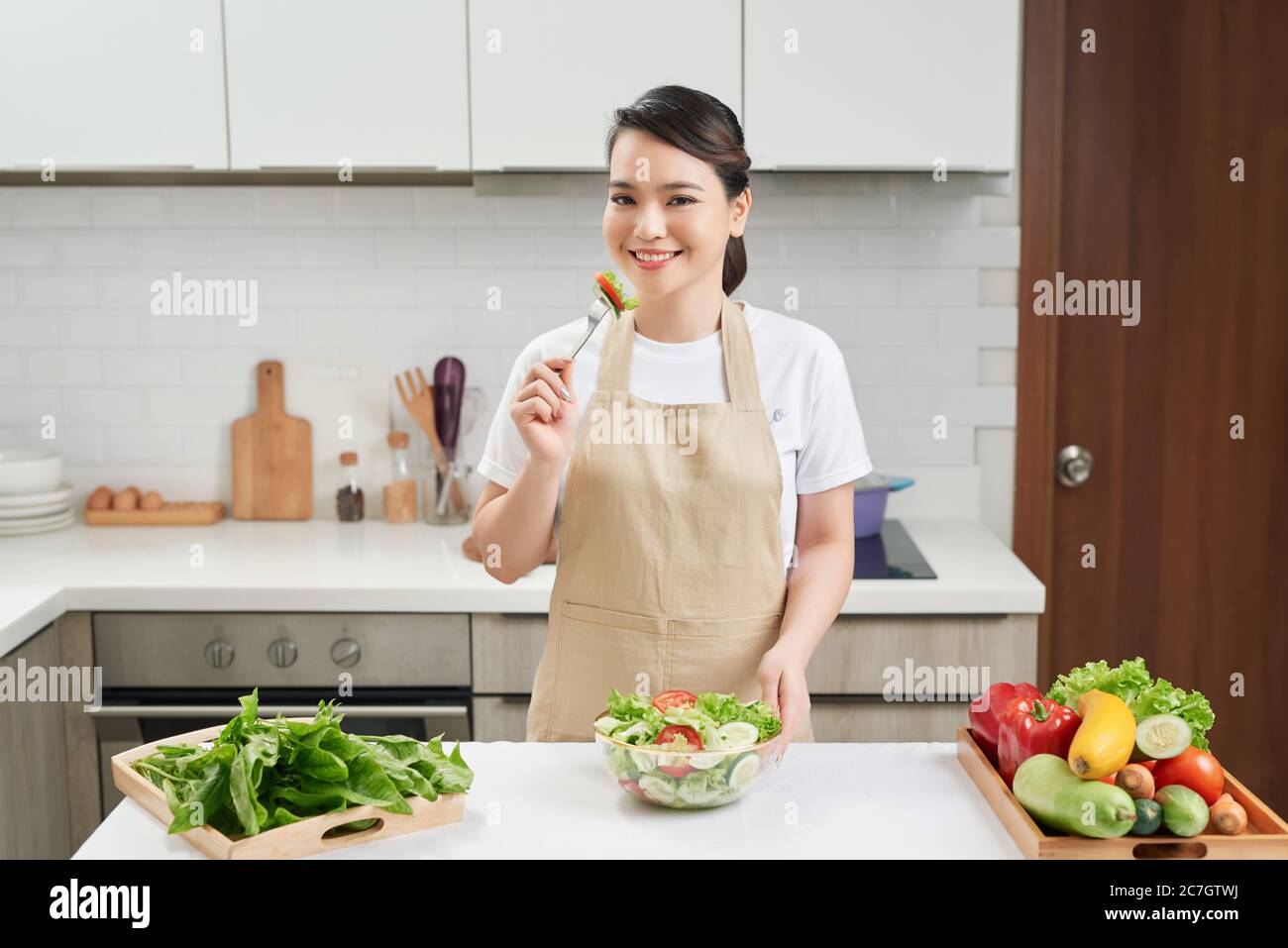 Photo verticale d'une jeune femme qui mange de la salade à la maison, un concept de régime Banque D'Images