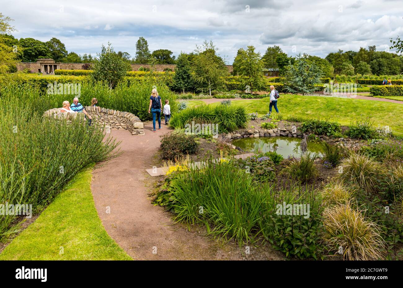 Visiteurs se détendant au bord de l'étang, jardin fortifié d'Amisfield, Haddington, East Lothian, Écosse, Royaume-Uni Banque D'Images