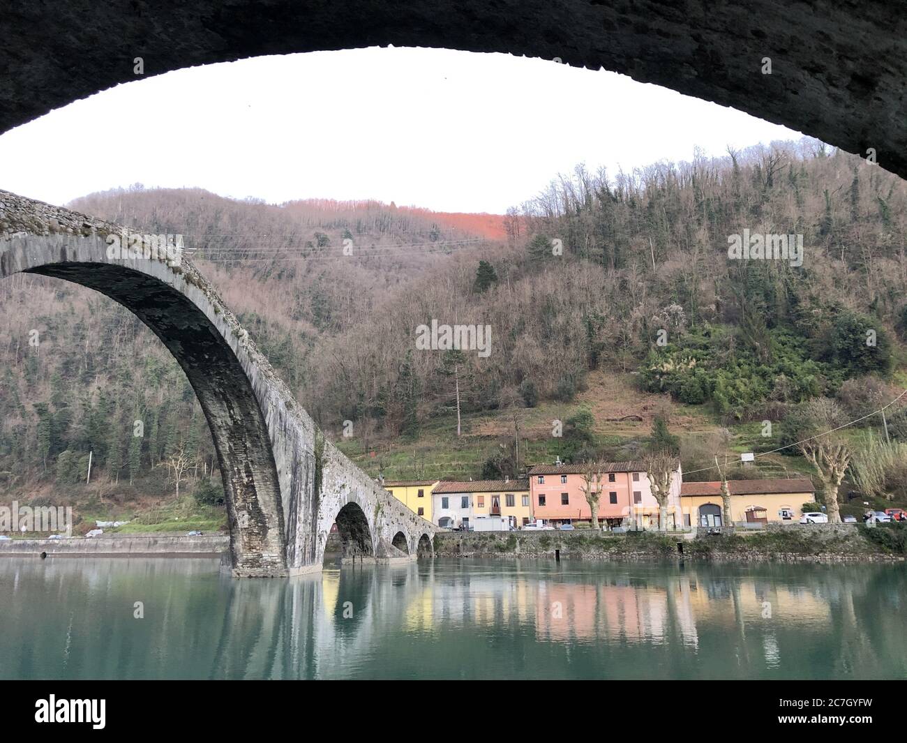 Pont du diable entouré de collines couvertes de verdure et de maisons Réflexion sur l'eau en Italie Banque D'Images