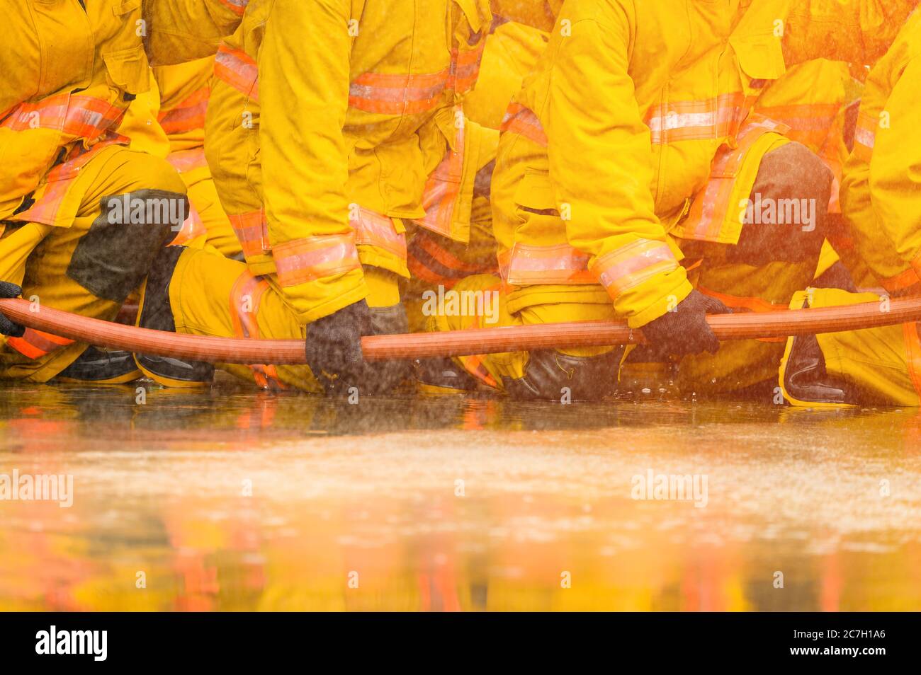 Pompier combattant la flamme d'incendie avec de l'eau et un extincteur dans l'atelier de formation, travail d'équipe et concept d'urgence Banque D'Images