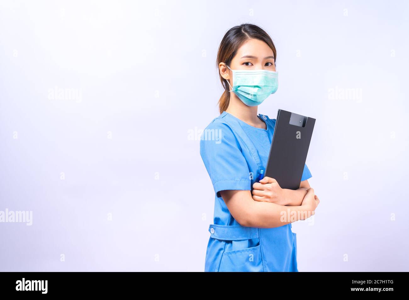 Portrait d'une jeune infirmière asiatique portant un masque chirurgical tenant un presse-papiers. Concept d'occupation et de carrière Banque D'Images
