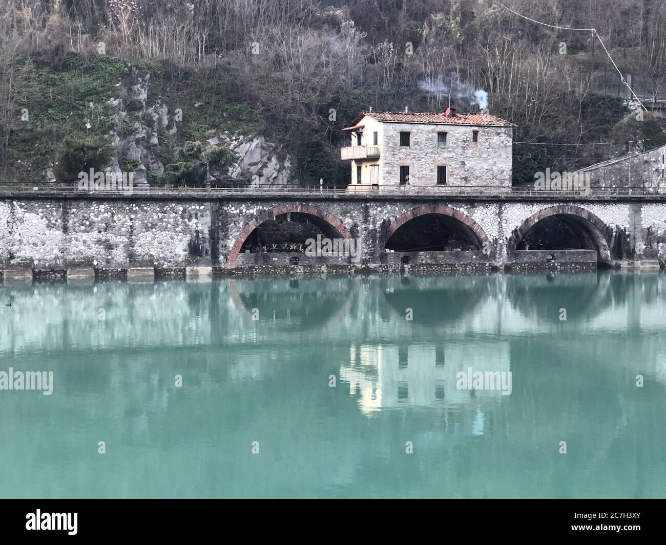 Pont du diable entouré de collines couvertes de verdure et de maisons Réflexion sur l'eau en Italie Banque D'Images