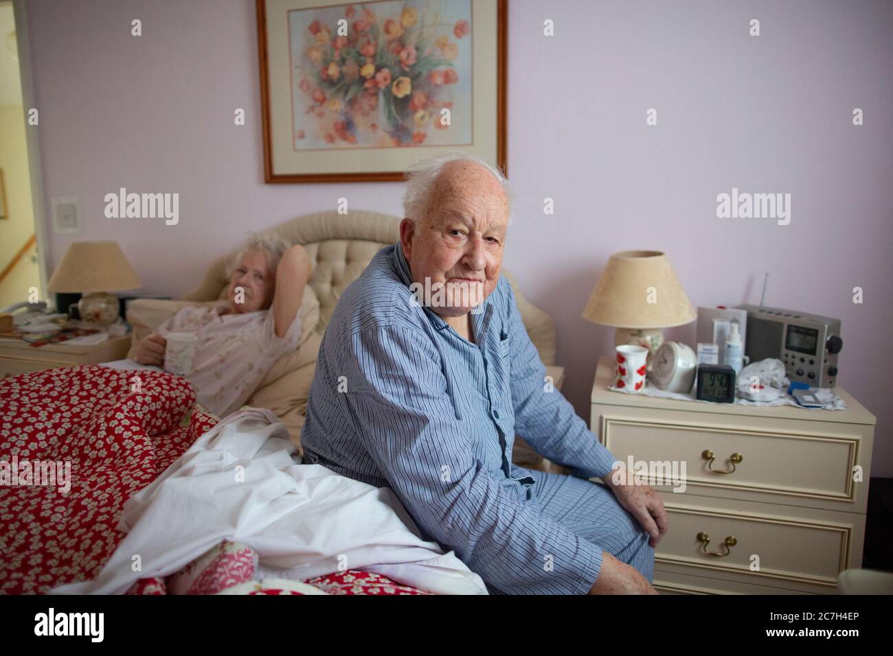 Un couple âgé dans les années 80 s'est assis sur le lit dans son pyjama avant de se lever dans le matin, Angleterre, Royaume-Uni Banque D'Images