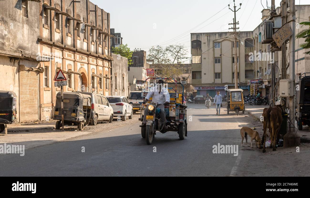 Junagadh, Gujarat, Inde - décembre 2018 : un homme conduit un tempo à trois roues transportant des marchandises à travers une rue vide d'un marché dans la vieille ville. Banque D'Images