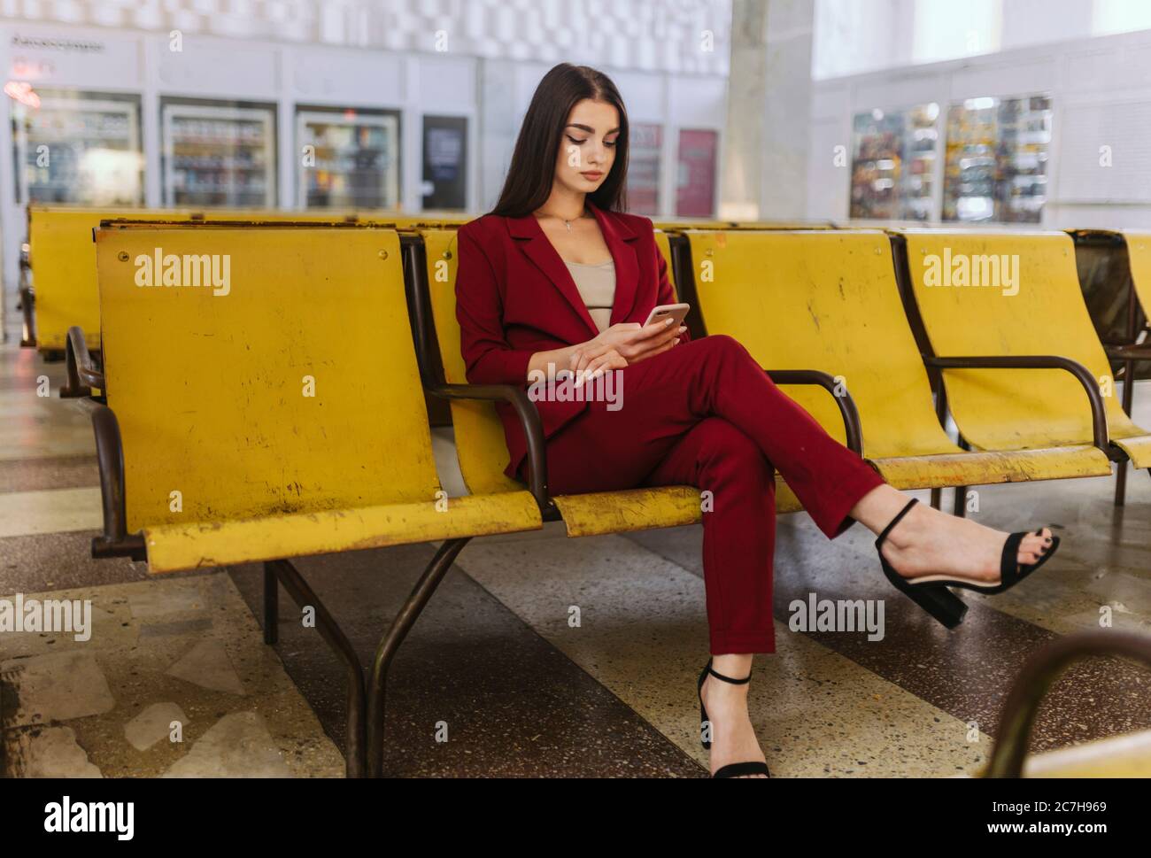 Femme assise dans une salle d'attente avec un téléphone entre ses mains Banque D'Images