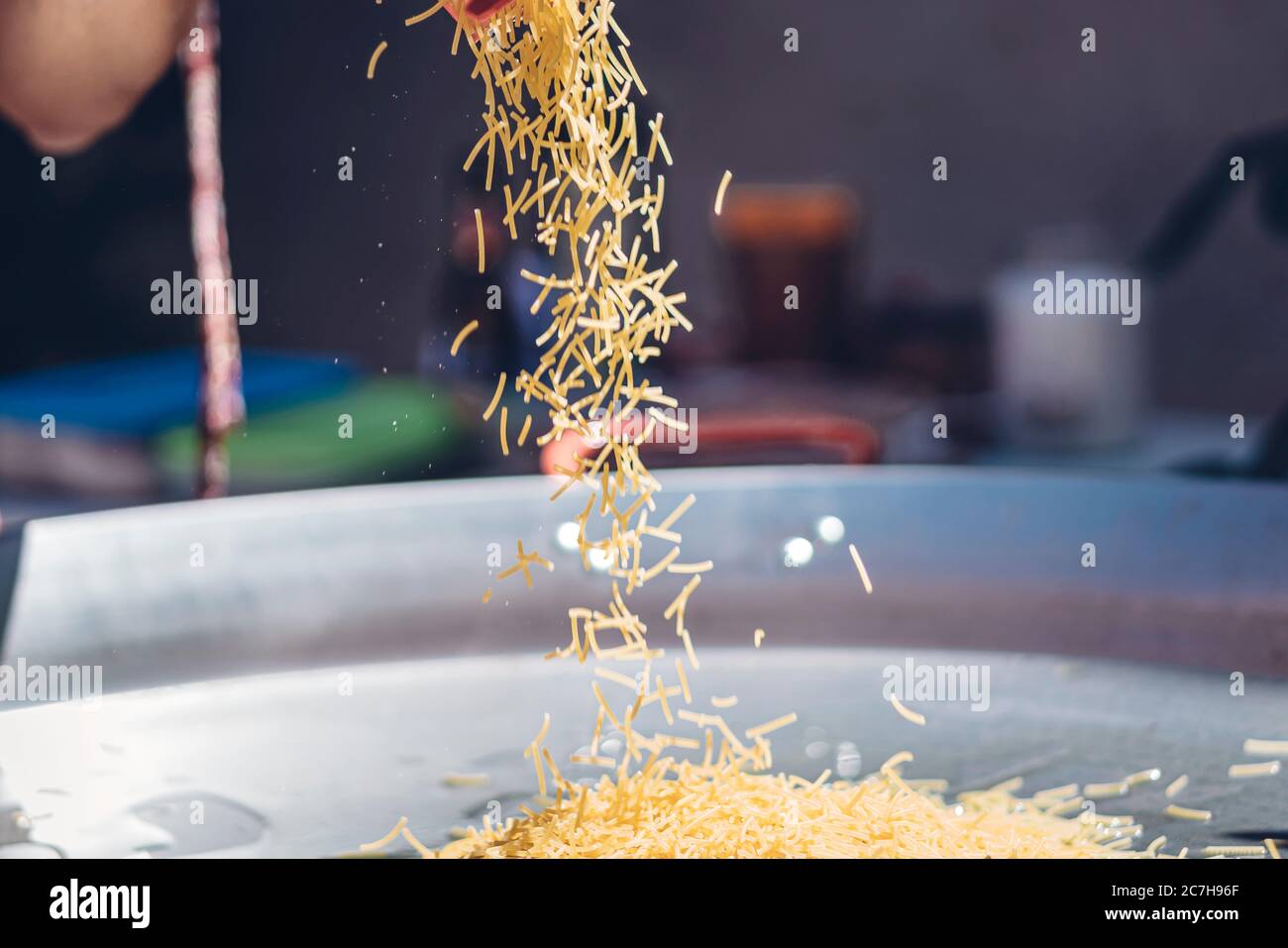 femme préparant une fideuá espagnole avec des crevettes et des nouilles calmars dans un moule à paella Banque D'Images