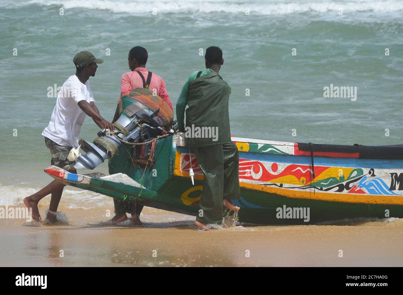 Pêcheurs artisanaux poussant les pirogues hors de l'eau à Lompoul, Sénégal Banque D'Images