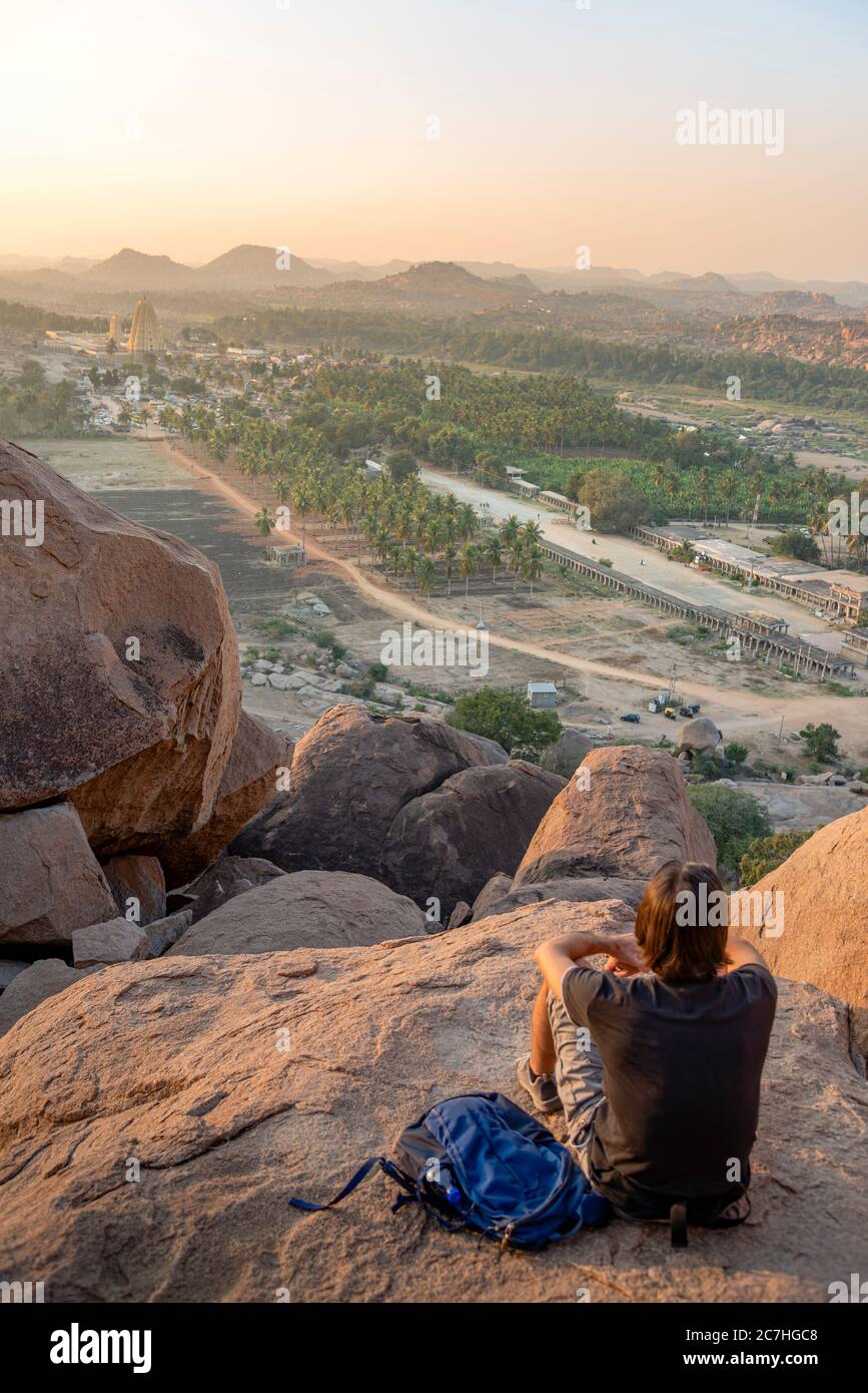 Watcher assis sur le rocher regarde la vallée au crépuscule Banque D'Images
