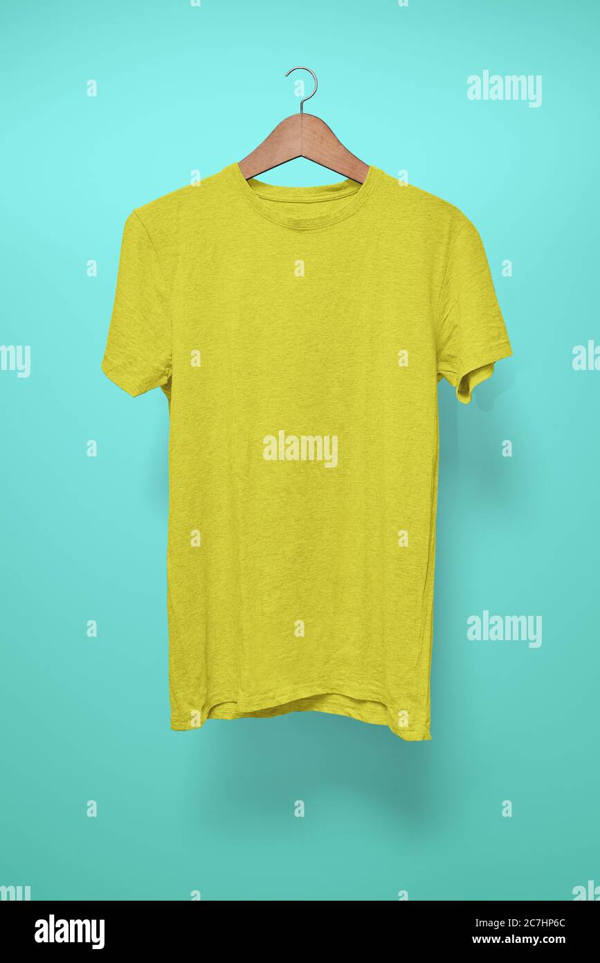 T-shirt jaune sur un cintre sur fond turquoise Banque D'Images
