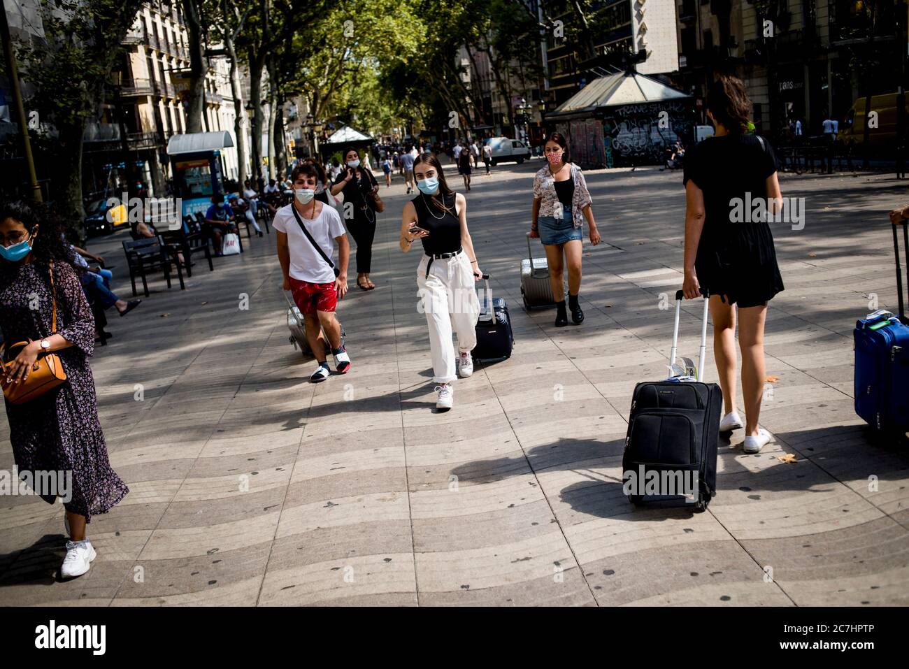 17 juillet 2020, Barcelone, Catalogne, Espagne: Les navetteurs traînant des valises à roulettes vont par Las Ramblas à Barcelone. Le gouvernement catalan a annoncé qu'il mettra en œuvre de nouvelles restrictions en raison de la hausse des cas de coronavirus dans la région. Le conseil touche quatre millions de personnes de Barcelone et de sa zone métropolitaine. Credit:Jordi Boixareu/Alamy Live News Banque D'Images