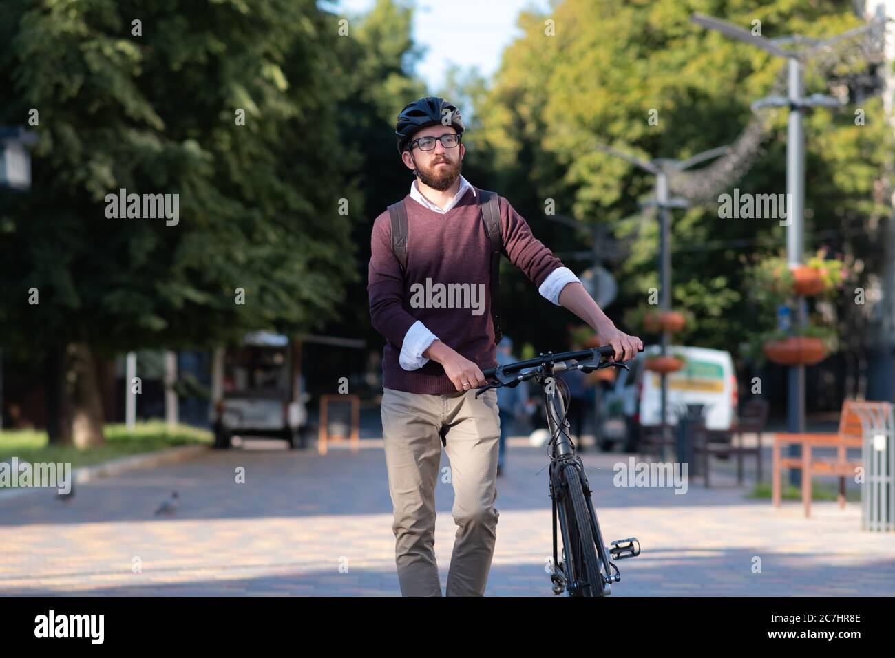 Portrait d'un homme de banlieue portant un casque de vélo dans une ville. Vélo en toute sécurité en ville, trajets à vélo, image active du mode de vie urbain Banque D'Images