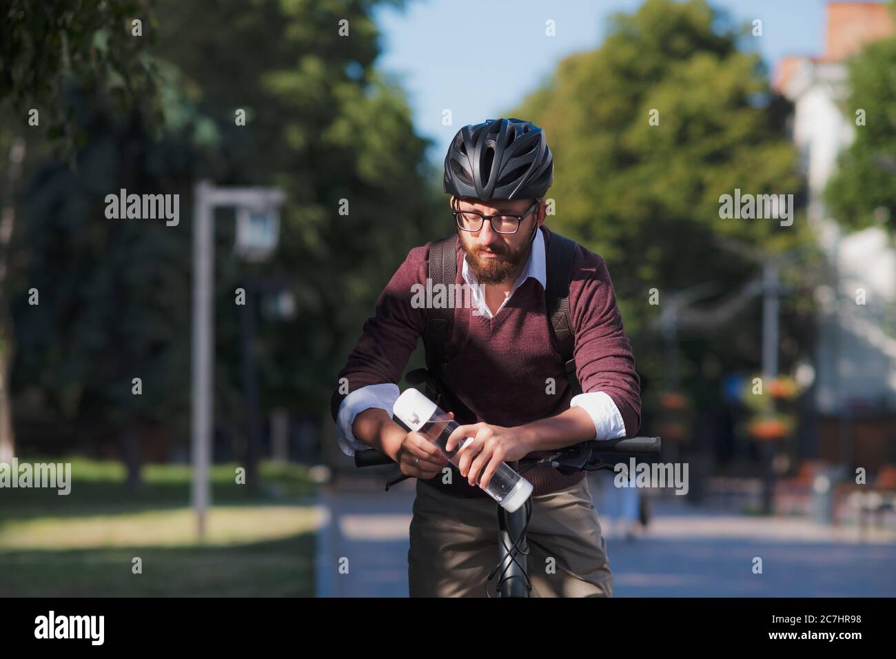 Homme de vélo avec une bouteille d'eau. Vélo en toute sécurité en ville, trajets à vélo, image active du mode de vie urbain Banque D'Images