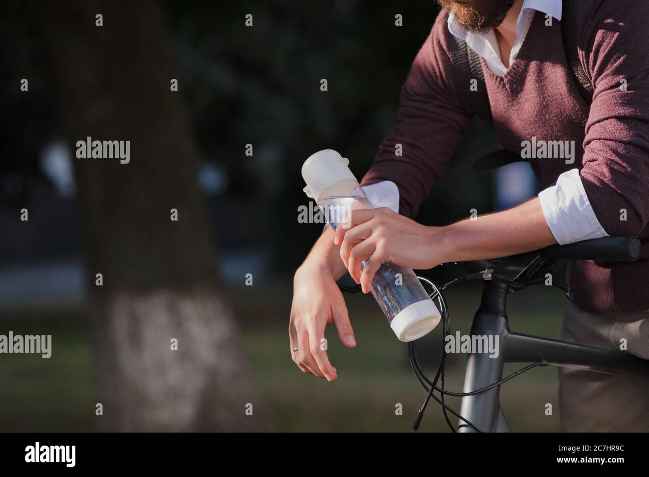 Bouteille d'eau dans les mains d'un vélo de transport. Rester hydraté, vie urbaine active, en utilisant un vélo dans la ville Banque D'Images