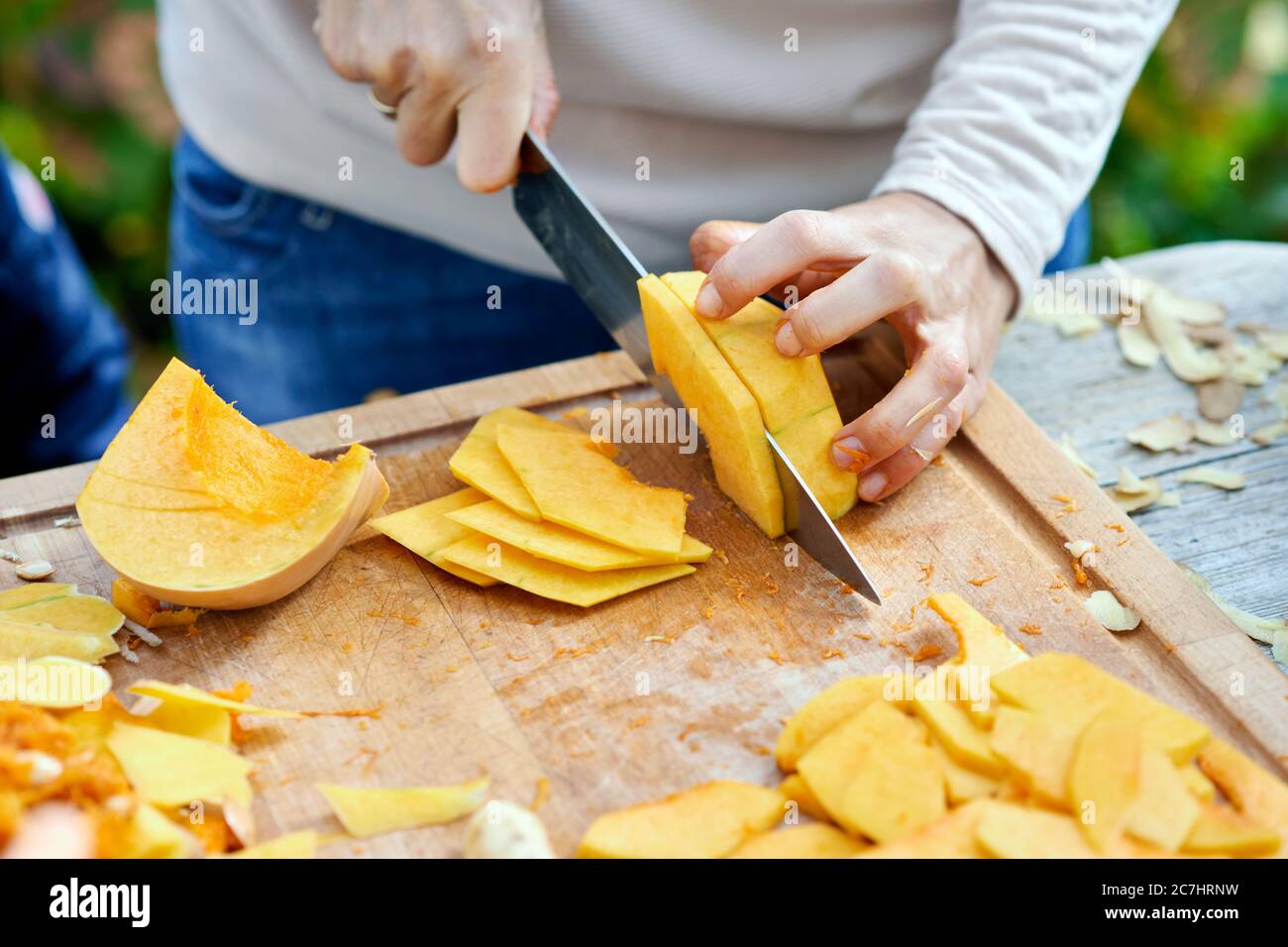 Une demi-citrouille et des quartiers de citrouille Hokkaido, séparés sur une planche en bois avec un couteau de chef Banque D'Images
